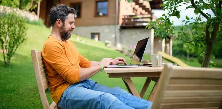 Man searching for job on laptop outside.